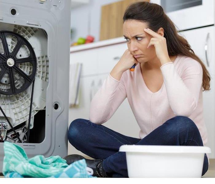 fustrated woman on floor looking at broken washer
